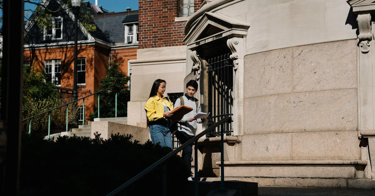 Deux étudiants discutant à l'extérieur d'un bâtiment du campus par une belle journée ensoleillée.