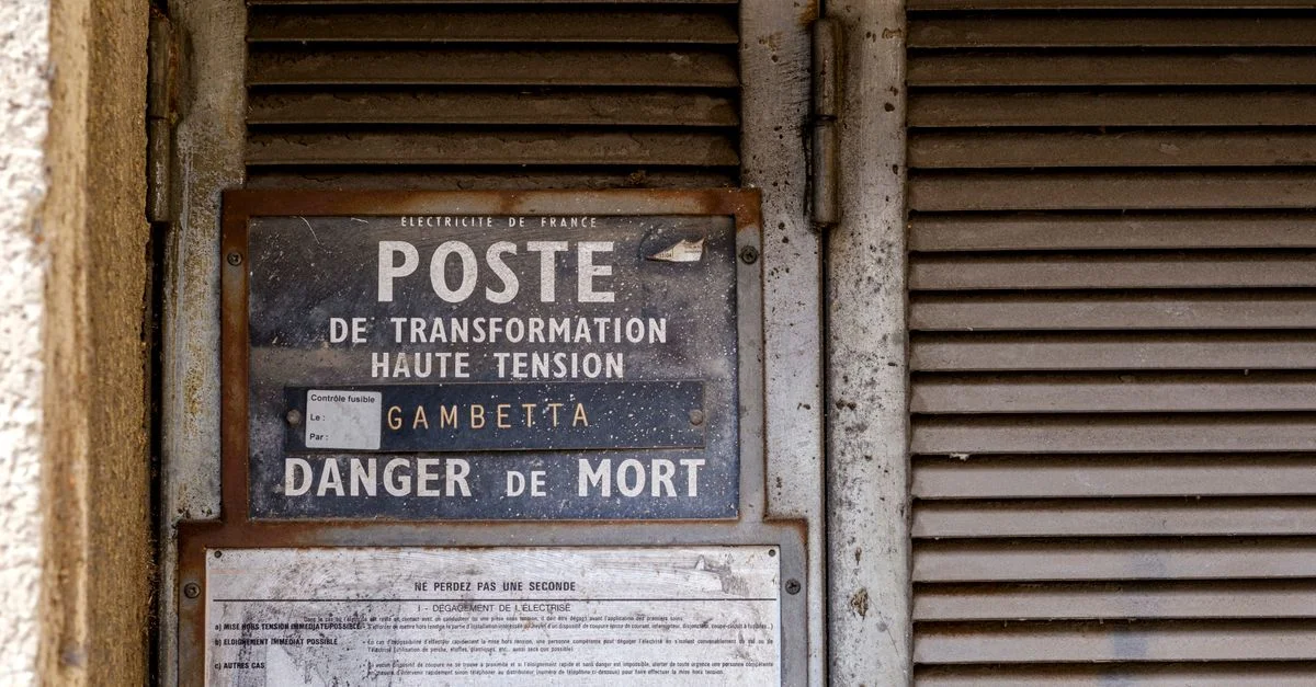 Panneau d'avertissement de haute tension rustique à Arles, en Provence, symbolisant le déclin urbain et l'histoire industrielle.