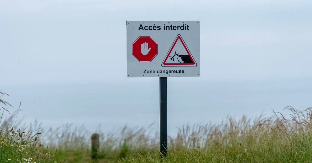 Panneau « Accès interdit » dans une zone herbeuse, signalant une zone dangereuse.